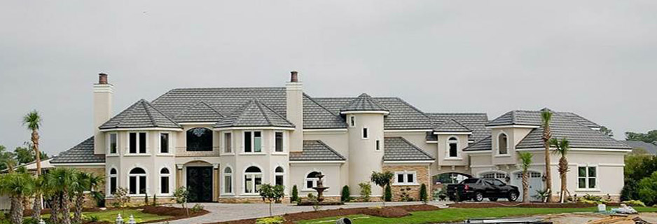 Large stucco mansion with tiled roof and driveway